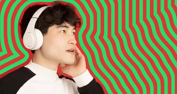 Asian young mans portrait on green red striped background. Concept of human emotions, facial expression, youth, sales, ad.