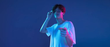 Kafkasyalı genç adam, Neon 'daki karanlık stüdyo arka planında portre çiziyor. İnsan duyguları kavramı, yüz ifadesi.