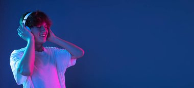 Kafkasyalı genç adam, Neon 'daki karanlık stüdyo arka planında portre çiziyor. İnsan duyguları kavramı, yüz ifadesi.