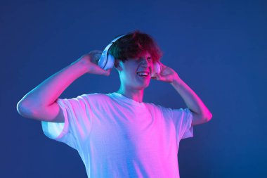 Kafkasyalı genç adam, Neon 'daki karanlık stüdyo arka planında portre çiziyor. İnsan duyguları kavramı, yüz ifadesi.