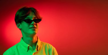 Kafkasyalı genç adam, Neon 'daki karanlık stüdyo arka planında portre çiziyor. İnsan duyguları kavramı, yüz ifadesi.