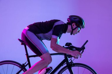 Bisikletçi, neon arka planda izole edilmiş bisiklet kullanıyor.