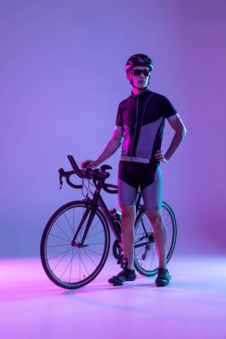 Bisikletçi, neon arka planda izole edilmiş bisiklet kullanıyor.