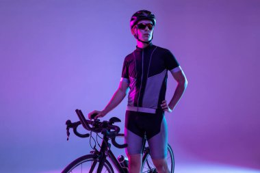 Bisikletçi, neon arka planda izole edilmiş bisiklet kullanıyor.