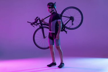 Bisikletçi, neon arka planda izole edilmiş bisiklet kullanıyor.