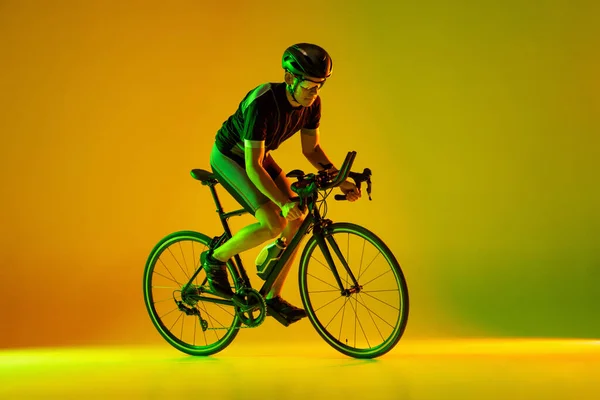 Ciclista montando uma bicicleta isolada contra fundo de néon — Fotografia de Stock