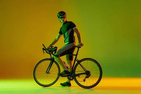 Ciclista montando uma bicicleta isolada contra fundo de néon — Fotografia de Stock