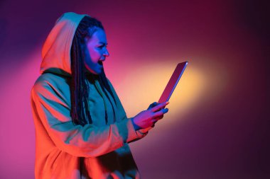 Elinde tablet var, çok heyecanlı. Siyah stüdyo arka planında neon ışıkta beyaz kadın portresi. Beyaz gömlekli güzel erkek model..