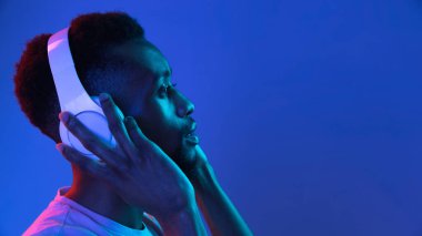 Siyah stüdyo arka planında Neon 'lu Afro-Amerikalı genç adam portresi. İnsan duyguları kavramı, yüz ifadesi, gençlik, satış, reklam.