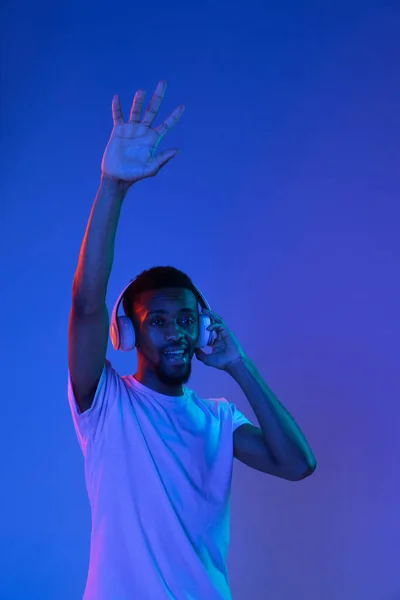 Afrykańsko-amerykański portret młodego człowieka na ciemnym tle studia w neonie. Pojęcie ludzkich emocji, ekspresji twarzy, młodzieży, sprzedaży, reklamy. — Zdjęcie stockowe