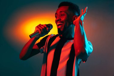 Kırmızı stüdyo arka planında Neon 'lu Afro-Amerikalı genç adam portresi. İnsan duyguları kavramı, yüz ifadesi, gençlik, satış, reklam.