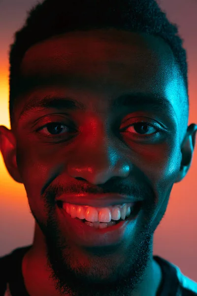 アフリカ系アメリカ人の若い男性がネオンの暗いスタジオの背景に肖像画。人間の感情の概念,顔の表情,若者,販売,広告. — ストック写真