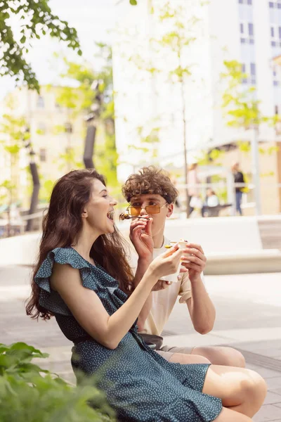 Счастливая привлекательная молодая пара романтически ест свежую пиццу на открытом воздухе. — стоковое фото