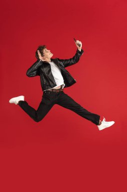 Her zaman cep telefonunda. Kırmızı stüdyonun arka planına atlarken telefonu eline alan genç bir adam. Hareket, hareket, hareket,