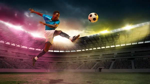 Gol! Erkek Afrikalı Socce, stadyumdaki bulutlu arka planda spor maçı sırasında atlayan futbolcu. — Stok fotoğraf