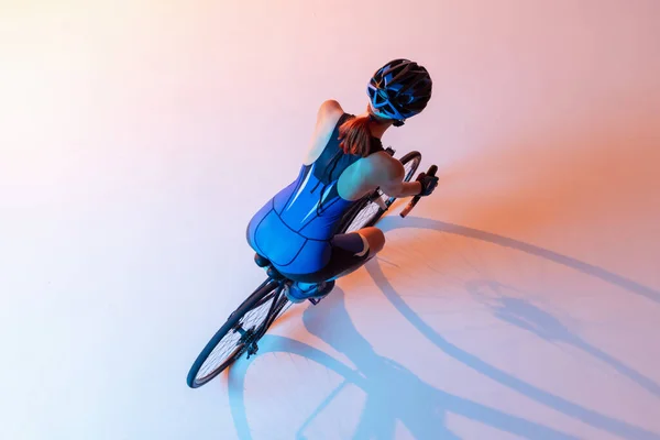 Hochwinkelaufnahme einer Radfahrerin auf einem Fahrrad isoliert vor neonfarbenem Hintergrund — Stockfoto