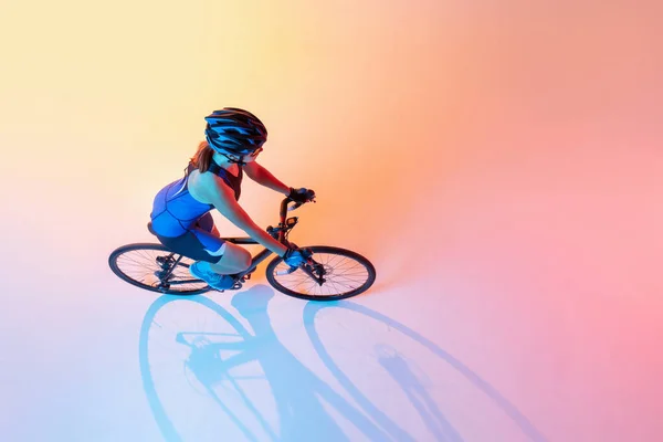 ネオンを背景に孤立した自転車に乗る女性サイクリストの高い角度ビュー — ストック写真