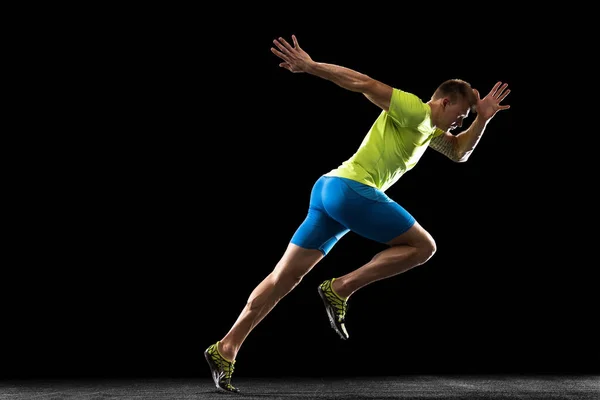 Кавказский профессиональный спортсмен, бегун тренируется изолированно на фоне черной студии. Мускулистый, спортивный человек. Концепция действия, движения, молодежи, здорового образа жизни. Копирование для рекламы. — стоковое фото
