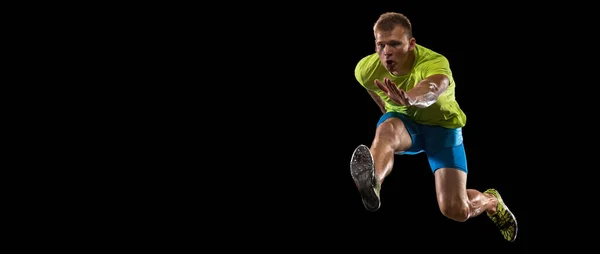 Atleta hombre atleta salta sobre la barrera aislada sobre fondo negro. — Foto de Stock