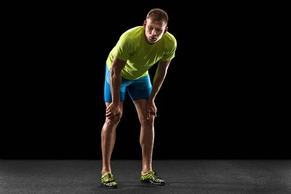 Atleta masculino profesional caucásico, corredor de pie aislado en el fondo del estudio negro. Hombre musculoso y deportivo. — Foto de Stock