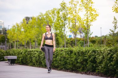 Genç bayan koşucu, şehrin sokaklarında bahar güneşinde bir atlet. Güzel beyaz kadın eğitimi, müzik dinlemek. Spor anlayışı, sağlıklı yaşam tarzı, hareket, aktivite.