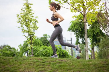 Genç bayan koşucu, atlet bahar güneşinde şehir caddesinde koşuyor. Güzel beyaz kadın eğitimi, müzik dinlemek. Spor anlayışı, sağlıklı yaşam tarzı, hareket, aktivite.