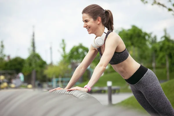 Jonge vrouwelijke loper, atleet is in de stad straat in de lente zonneschijn. Prachtige blanke vrouw training, luisteren naar muziek. Begrip sport, gezonde levensstijl, beweging, activiteit. — Stockfoto