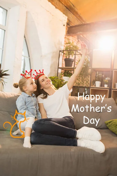 Mujer sonriente y niña, madre e hija linda en casa. Tiempo en familia, convivencia, crianza y concepto de infancia feliz. Diseño de la tarjeta de felicitación para el día de las madres. —  Fotos de Stock