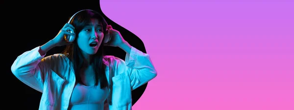Young beautiful girl listening to music isolated over purple black background in neon light. Concept of beauty, fashion,ad. Flyer — Stock Photo, Image