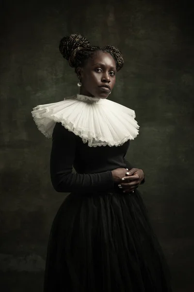 Porträt einer mittelalterlichen afrikanischen jungen Frau in schwarzem Vintage-Kleid mit großem weißen Kragen, die isoliert auf dunkelgrünem Hintergrund posiert. — Stockfoto