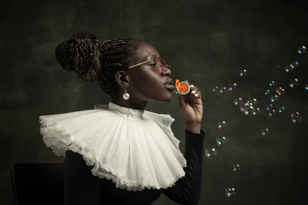 Porträt einer mittelalterlichen afrikanischen jungen Frau in schwarzem Vintage-Kleid mit großem weißen Kragen, die isoliert auf dunkelgrünem Hintergrund posiert. Blasen blasen — Stockfoto