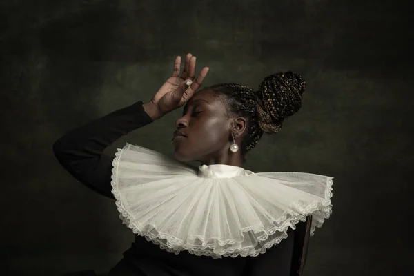 Porträt einer mittelalterlichen afrikanischen jungen Frau in schwarzem Vintage-Kleid mit großem weißen Kragen, die isoliert auf dunkelgrünem Hintergrund posiert. Furchtbare Kopfschmerzen — Stockfoto