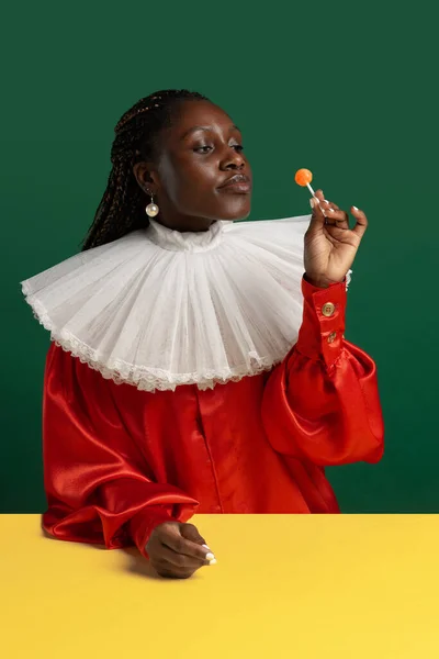 一位身穿鲜红色复古服装，白领大领的非洲年轻女子在绿色背景下显得孤立无援。时代,时尚,幽默,广告的比较概念. — 图库照片