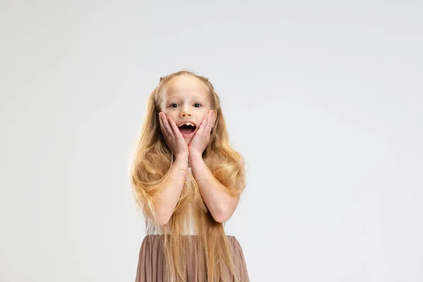 Belle petite fille en robe élégante moderne posant isolée sur fond de studio blanc. Concept d'enfance heureuse. — Photo