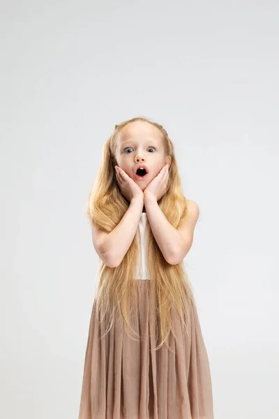 Mooi klein meisje in moderne stijlvolle jurk poseren geïsoleerd op witte studio achtergrond. Gelukkige jeugd concept. — Stockfoto
