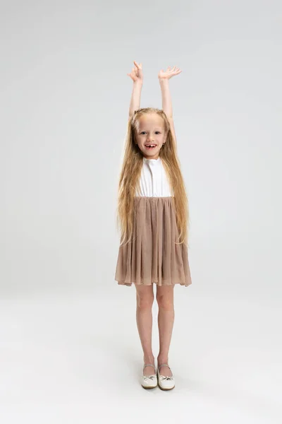 Belle petite fille en robe élégante moderne posant isolée sur fond de studio blanc. Concept d'enfance heureuse. — Photo