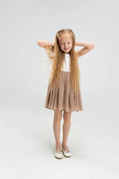 Belle petite fille en robe élégante moderne posant isolée sur fond de studio blanc. Concept d'enfance heureuse. — Photo