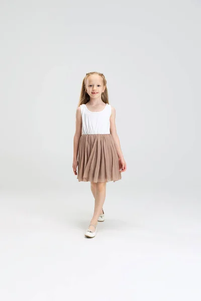 Девочка в современном стильном платье позирует на белом студийном фоне. Концепция счастливого детства. — стоковое фото