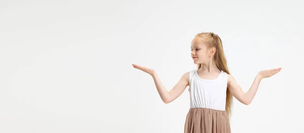 Retrato de media longitud de linda niña en vestido moderno y elegante posando aislado sobre fondo de estudio blanco. Concepto de infancia feliz. —  Fotos de Stock