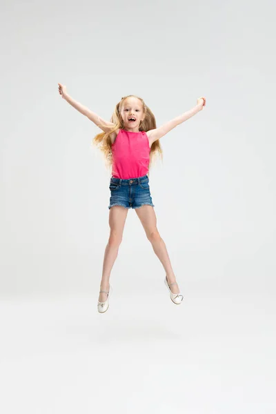 Menina bonita em roupas casuais pulando isolado no fundo do estúdio branco. Conceito de infância feliz. — Fotografia de Stock