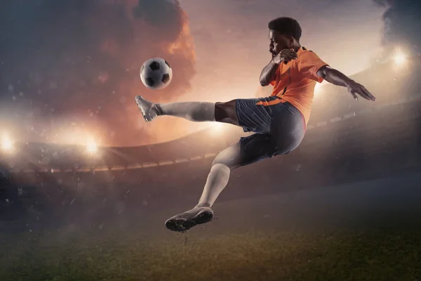 男子足球、足球运动员在漆黑的天空背景下在体育场跳起球 — 图库照片