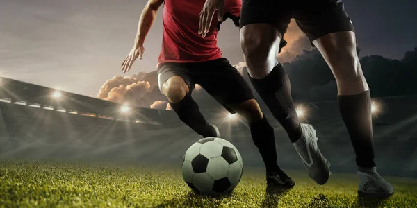 Two male soccer, football players dribbling ball at the stadium during sport match on dark sky background. — Stock Photo, Image