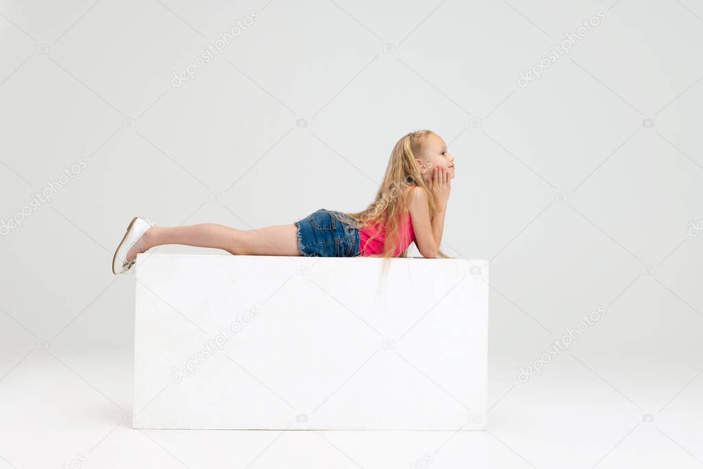 One beautiful little girl in casual clothes isolated on white studio background. Happy childhood concept.