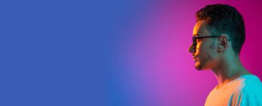 Latina 'lı genç erkeklerin gradyan pembe arkaplanda neon ışıkta portresi. Yan görüş. El ilanı