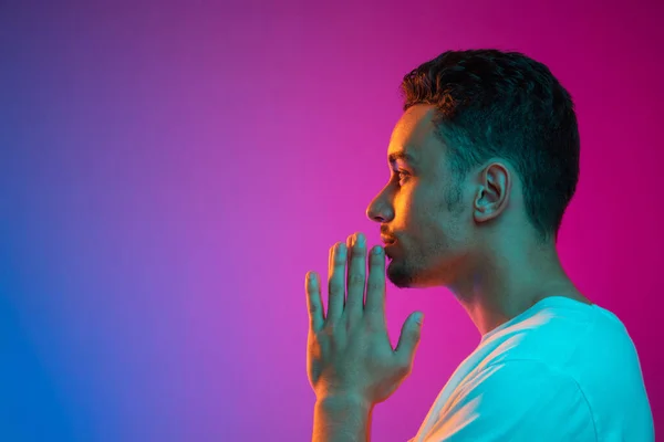 Latina young mans portrait on gradient purple pink background in neon light. Side view — Stock Photo, Image