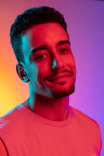 Close-up portrait of Latina young man isolated on gradient yellow purple background in neon light. Concept of emotions, facial expression — Stock Photo, Image