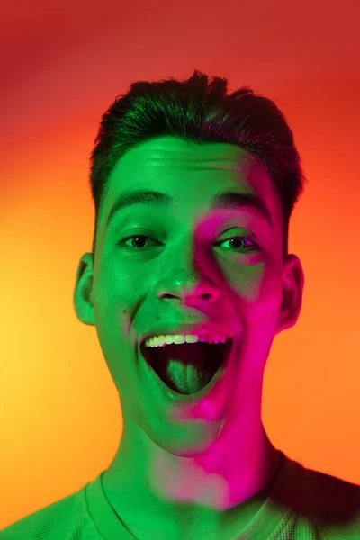 Close-up jovem caucasiano gritando com alegria isolado no fundo do estúdio laranja em luz de néon. Conceito de emoções humanas, expressão facial. Uau. — Fotografia de Stock