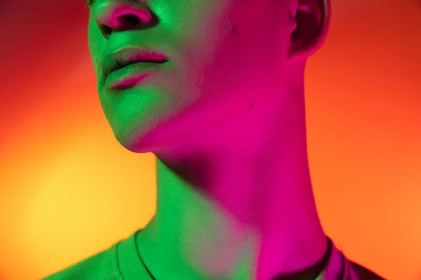 Zugeschnittenes Bild eines kaukasischen jungen Mannes isoliert auf orangefarbenem Studiohintergrund im Neonlicht. Konzept menschlicher Emotionen, Mimik. — Stockfoto