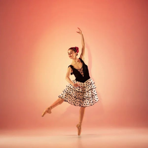 Jovem e incrivelmente bela bailarina está posando e dançando no estúdio vermelho cheio de luz. — Fotografia de Stock