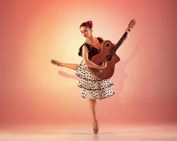 Jovem e incrivelmente bela bailarina está posando e dançando no estúdio vermelho cheio de luz. — Fotografia de Stock